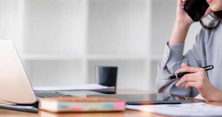 Businesswoman hand using digital tablet in home office room. Female entrepreneur using digital tablet and computer. Analyzing online marketing and E-commerce business.