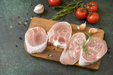 Fresh steaks raw turkey with rosemary and spices on a dark stone tabletop. Raw beef meat steaks for grilling.