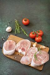 Fresh steaks raw turkey with rosemary and spices on a dark stone tabletop. Raw beef meat steaks for grilling.