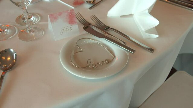 White tablecloth with name card and heart shape in white plate in wedding festive
