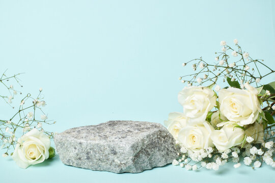Podium for product presentation. Minimalistic stone scene with white roses on a gray background. Showcase for the exhibition. Space for copying. Flat position, top view.