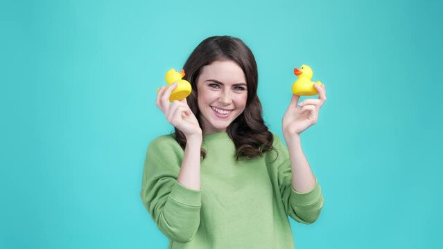 Lady play two plastic duck bird kiss face isolated cyan color background