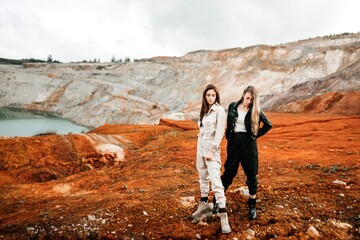 Girls in a post-apocalyptic place, a quarry with red earth and stones in work clothes