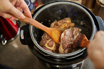 Ossobuco with spindle Beef is fried in pressure cooker and mixed with wooden spatulas. French...