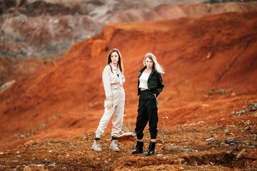 Girls in a post-apocalyptic place, a quarry with red earth and stones in work clothes