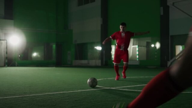 Slow motion, training day on the football club, young guys play football indoor stadium, man successfully passed the ball, low angle view.