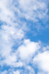 Vertical shot of a blue sky with white clouds