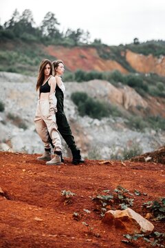 Girls in a post-apocalyptic place, a quarry with red earth and stones in work clothes