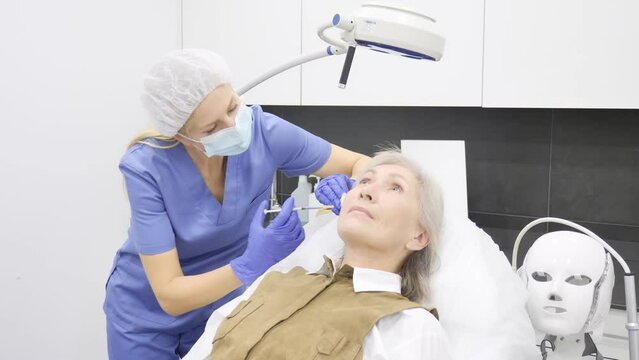 Senior woman recieving botulinotherapy during doctor's appointment in cosmetological clinic. 