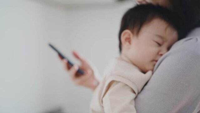 赤ちゃんをあやしながらスマートフォン操作をする女性