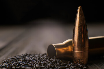 Macro shot of cartridge case, bullet and gunpowder on wooden background, soft focus