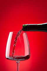 Fototapeta premium Red wine pouring from bottle into glass
