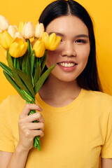 woman in a yellow t-shirt t-shirt with a bouquet of flowers holiday yellow background unaltered