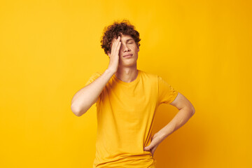 Young curly-haired man yellow t-shirt fashion hand gestures isolated background unaltered