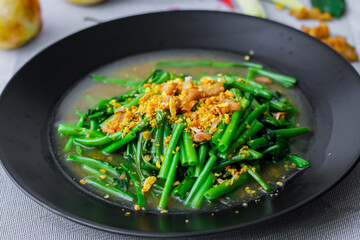 Stir-fried morning glory in a black dish 