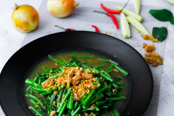Stir-fried morning glory in a black dish 