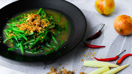 Stir-fried morning glory in a black dish 