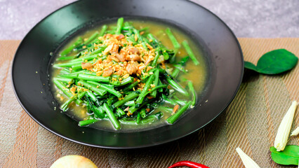 Stir-fried morning glory in a black dish 