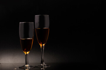 Two glass glasses of different sizes with an alcoholic drink on a black background. - 487028033