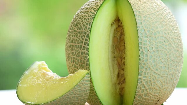 Green Melon on blurred greenery background, Cantaloupe Melon fruit in Bamboo mat on wooden table in garden.