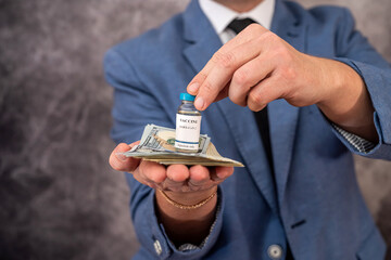 Stylish man with strong hands in a suit carries the vaccine in a jar and dollars for it.