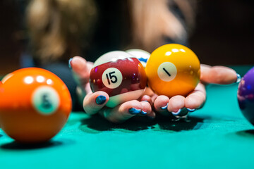 hands of  young slender girl chasing billiard balls on a spacious table in the billiard room.