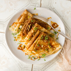 a plate of thin pancakes with salted caramel sauce on a light table