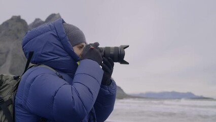 Photographer Raising Camera To Eye To Shoot On Beach