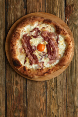 Carbonara pizza with bacon and egg on wooden background