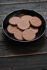 Chocolate flavored cookies Served in a black plate on a wooden table.