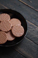 Chocolate flavored cookies Served in a black plate on a wooden table.