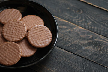 Chocolate flavored cookies Served in a black plate on a wooden table.
