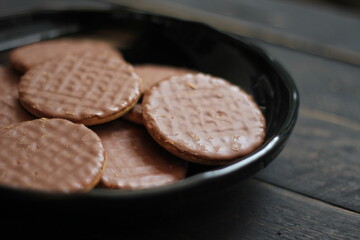 Chocolate flavored cookies Served in a black plate on a wooden table.