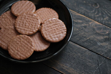 Chocolate flavored cookies Served in a black plate on a wooden table.
