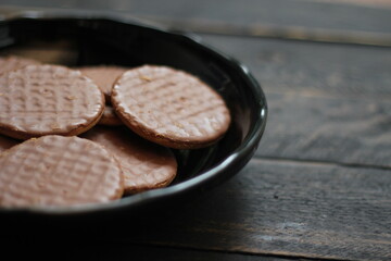 Chocolate flavored cookies Served in a black plate on a wooden table.