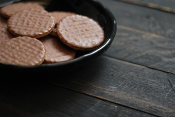 Chocolate flavored cookies Served in a black plate on a wooden table.