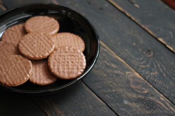Chocolate flavored cookies Served in a black plate on a wooden table.