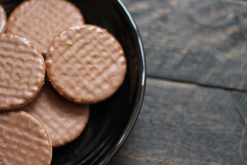 Chocolate flavored cookies Served in a black plate on a wooden table.