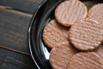 Chocolate flavored cookies Served in a black plate on a wooden table.