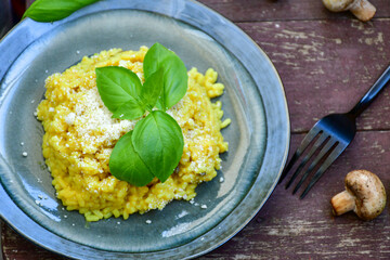  Italian  creamy risotto milanese  with parmesan cheese and fresh basil on rustic background