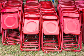 a pile of red folding chairs in the field