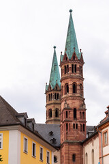 Brick colored towers with bronze green roofs at Würzburger Cathedral or Würzburger Dom between two apartment houses seen from the nave side
