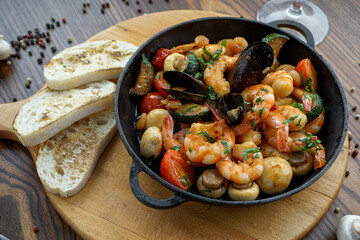 shrimps with mussels, mushrooms and cherry tomatoes in a frying pan
