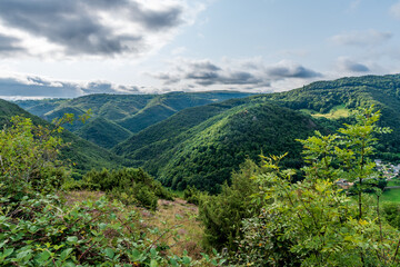 Fototapeta na wymiar Panorama sur les montagnes recouvertes de forets pris depuis le sentier au loups et dominant la vallée de Courgoul dans le puy de dôme en Auvergne par une journée orageuse