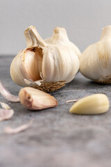 Group of garlic cloves on a gray stone, one of them with a clove already peeled on the table. Selective focus. High quality photo