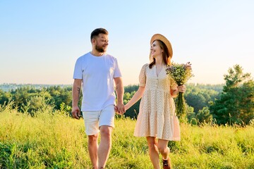 Happy middle age couple holding hands, summer nature wild meadow