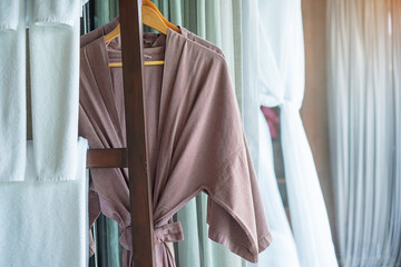 Closeup clean bathrobe and towel hanging in wooden wardrobe at luxury hotel. Relax and travel concept
