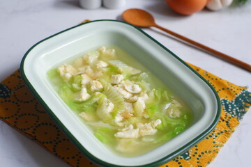 a bowl of cabbage and egg soup in white background 