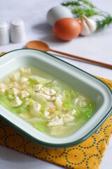 a bowl of cabbage and egg soup in white background 