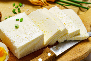 tasty lunch in rural style, healthy food - sliced feta cheese, eggs and green leek, cooked food on a white wooden boards